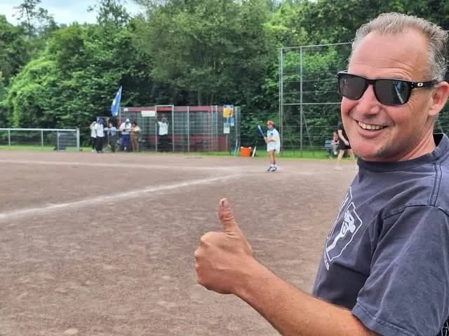 Vrijwilliger van Falcons langs het veld, met spelers op de achtergrond
